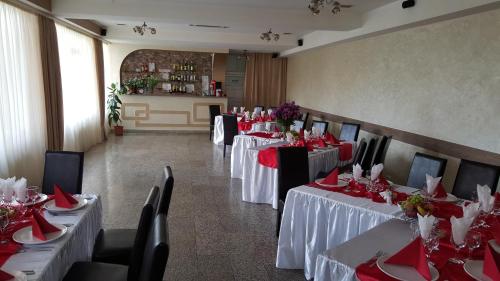 un comedor con mesas y sillas con servilletas rojas en Pensiune Restaurant Avangarde, en Piteşti