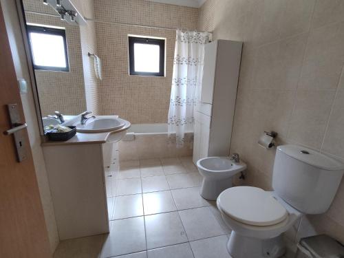 a bathroom with a toilet and a sink and a tub at 4B Alto dos Navegantes - Casas & Papéis in Armação de Pêra