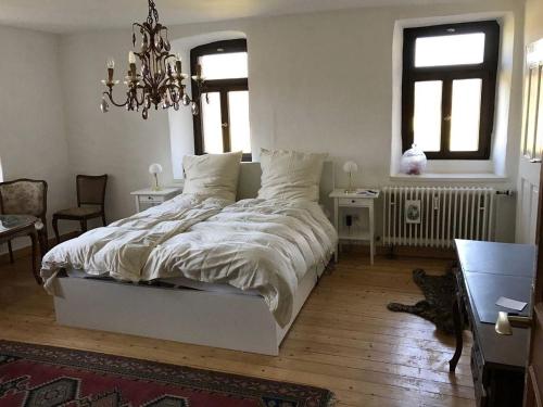 um quarto com uma grande cama branca e um lustre em Schöne Ferienwohnung in Sinsheim mit Großer Terrasse em Sinsheim