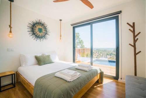 a bedroom with a bed and a large window at Caju Villas Montargil - Villa Farinha Branca in Montargil
