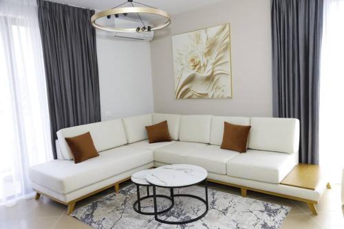 uma sala de estar com um sofá branco e uma mesa em Cozy Apartments em Tirana