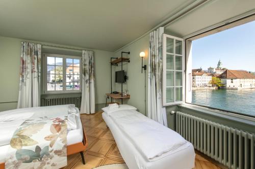 a bedroom with a bed and a large window at Hotel an der Aare Swiss Quality in Solothurn