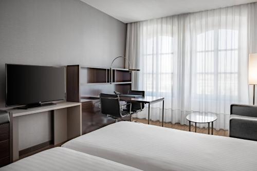 トリノにあるAC ホテル トリノ ア マリオット ライフスタイル ホテルのベッド、デスク、テレビが備わるホテルルームです。