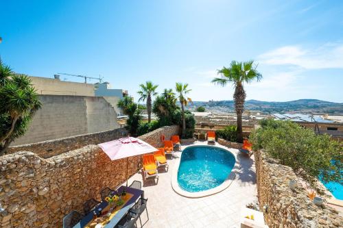 an outdoor swimming pool with chairs and an umbrella at La Rustica Holiday Home in Xagħra