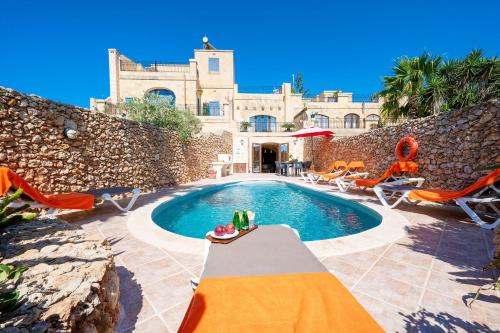 a swimming pool in front of a house at La Rustica Holiday Home in Xagħra