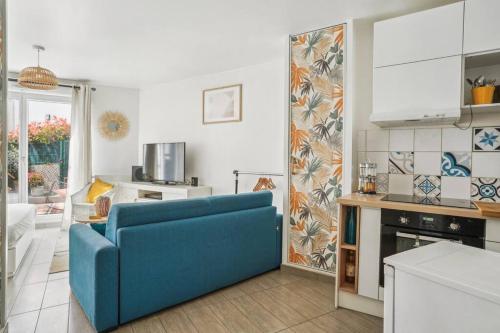 un salon avec un canapé bleu et une cuisine dans l'établissement 10 minutes à pied du marché aux puces de Paris, à Saint-Ouen