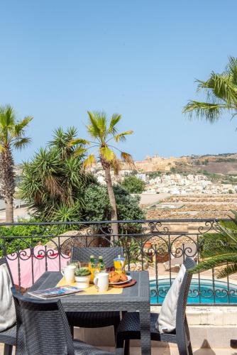 a table with food on a balcony with a view of the ocean at La Rustica Holiday Home in Xagħra