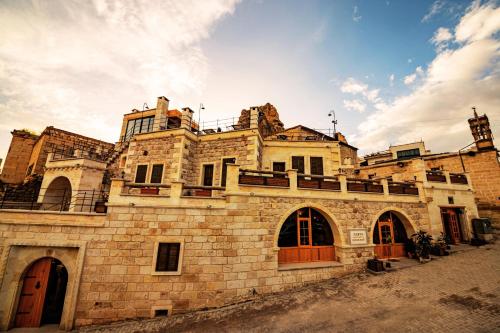 an old stone building with a clock tower in the background at Janus Cappadocia in Nevsehir