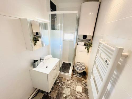une salle de bain blanche avec un lavabo et un miroir dans l'établissement Cosy Appartement Vue mer, Clim, Place de Parking, à Sanary-sur-Mer