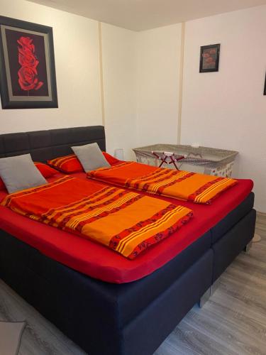 a large bed with red and orange blankets on it at Charlottenhöhe Apartment in Rottweil