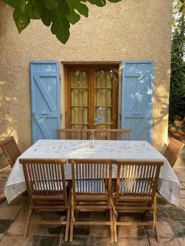 une table avec quatre chaises et des portes bleues dans l'établissement 2 PIECES TERRASSE ET PISCINE PRIVATIVES DANS MAISON TRADITIONNELLE, à Châteauneuf-le-Rouge