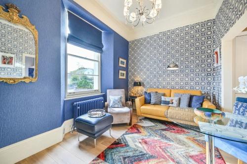 een woonkamer met blauwe muren en een bank bij Große Wohnung in Torquay mit Terrasse, Grill und Garten in Torquay