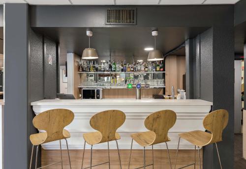 a bar with four chairs in front of a counter at B&B HOTEL Rouen Centre Rive Droite in Rouen