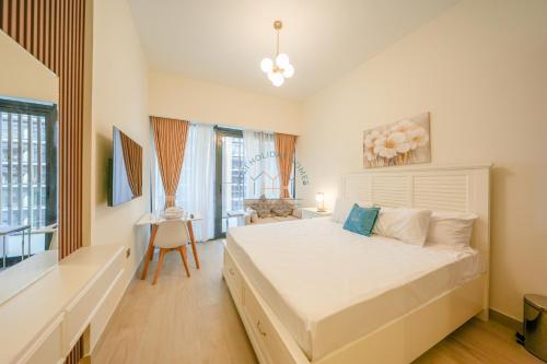 a bedroom with a large white bed and a desk at Yogi - Studio in Azizi Riviera - MBR City & Pool in Dubai