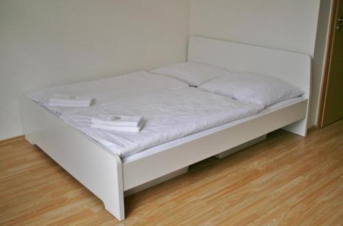 a white bed in a room with a wooden floor at ADC Design Apartmány in Brno