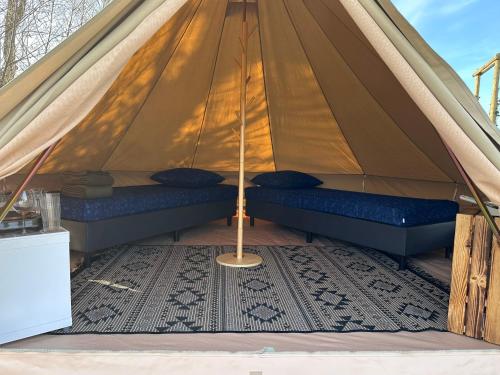 Bell Tent في Warmond: خيمة فيها وسادتين وسجادة