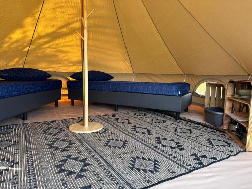 a tent with two beds and a rug at Bell Tent in Warmond
