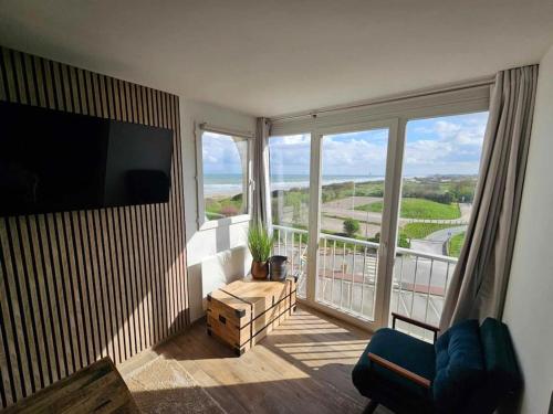 ein Wohnzimmer mit einem großen Fenster mit Blick auf das Meer in der Unterkunft Appartement vue mer et dunes in Dunkerque
