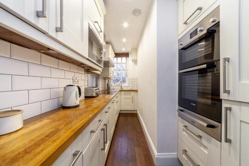 una cocina con armarios blancos y horno negro en The St John's Wood Apartment en Londres
