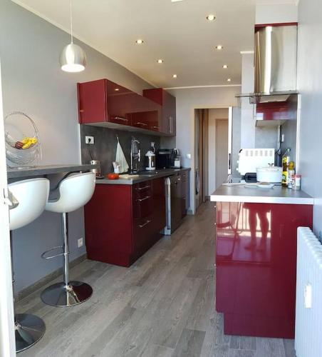 une cuisine avec des armoires rouges et un comptoir blanc dans l'établissement Appartement BAILA, proche de St Emilion et Bordeaux, à Libourne
