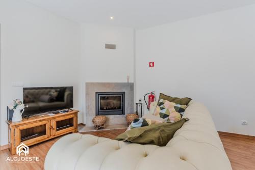 a living room with a white couch and a tv at Villa Penafirme - Santa Cruz in Santa Cruz