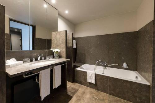 een badkamer met een bad, een wastafel en een bad bij Unique Luxury Central Flat in Brussel