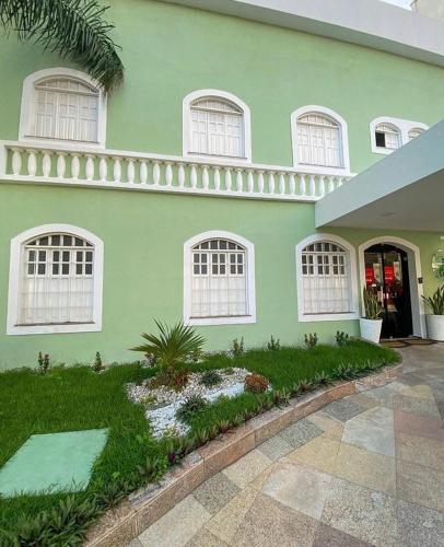 a green house with white windows and a courtyard at Hotel Cocal in Fortaleza
