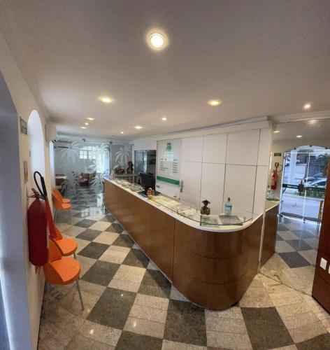 un vestíbulo con una barra larga con sillas naranjas en Hotel Cocal, en Fortaleza
