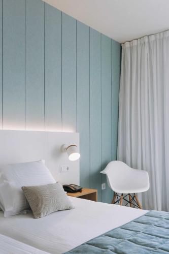 a bedroom with a bed and a white chair at Alua Village Fuerteventura - All Inclusive in Playa Jandia