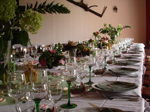 une longue table avec des verres à vin et des fleurs dessus dans l'établissement Hôtel le Dauphin, à Moulins-la-Marche
