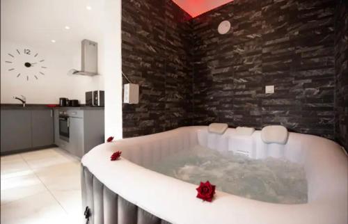 a bath tub in a room with a brick wall at La belle Hirondelle - Love Room Jacuzzi in Morangis
