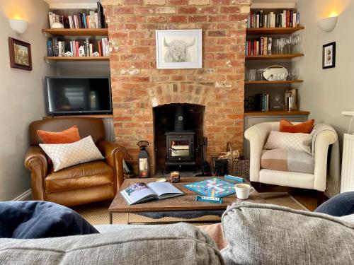 a living room with a brick fireplace and a table at Romantic cosy cottage close to Oxford and The Cotswolds in Cuddesdon