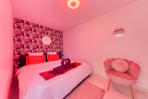 Dormitorio rosa con cama y silla en La belle Hirondelle - Love Room Jacuzzi, en Morangis
