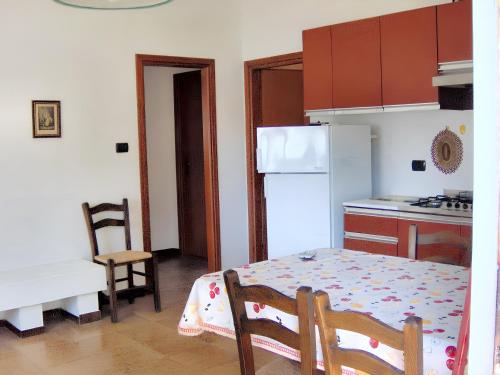 uma cozinha com uma mesa e um frigorífico branco em 3 bedrooms house at Lacona 100 m away from the beach with enclosed garden em Lacona