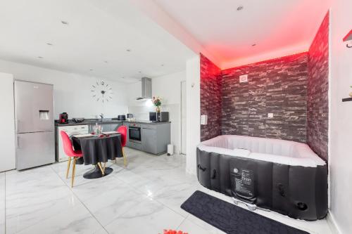 une chambre avec une baignoire et une table et une cuisine dans l'établissement La belle Hirondelle - Love Room Jacuzzi, à Morangis