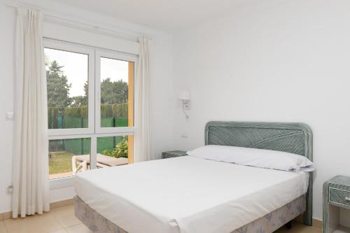 a white bedroom with a bed and a window at Seraph by ON Travel in Oliva