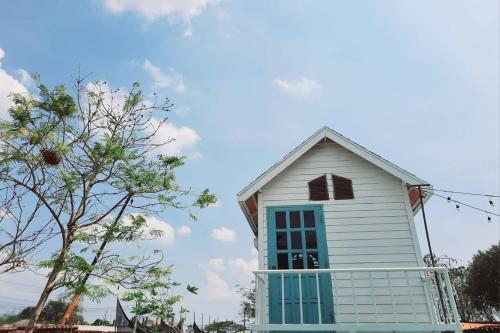 a small white house with a window and a tree at See Sky Resort in Ban Sao Thong