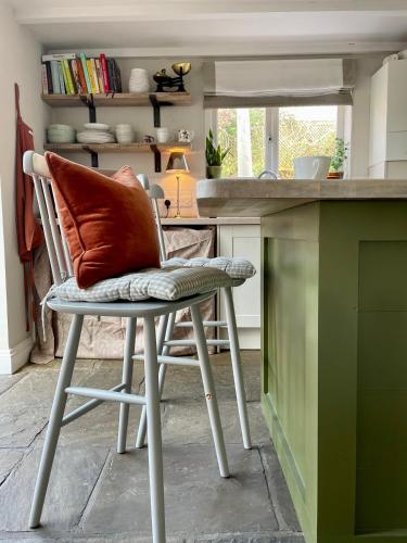 a chair with a pillow on it in a kitchen at Romantic cosy cottage close to Oxford and The Cotswolds in Cuddesdon