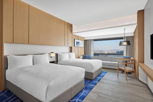 a hotel room with two beds and a couch at Courtyard by Marriott Xiamen in Xiamen