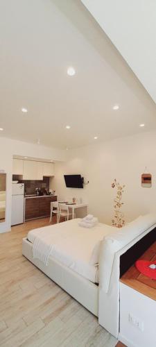a white bedroom with a large bed and a kitchen at BARBARA Classy Apartments 103, Wellness in Siracusa