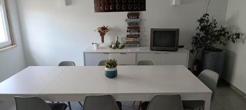a room with two white tables and a tv at Sal Guest House in Costa da Caparica