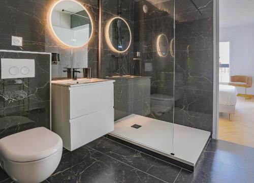 La salle de bains est pourvue de toilettes, d'un lavabo et de miroirs. dans l'établissement Casa Isulana-Standing-Hyper Centre, à LʼÎle-Rousse