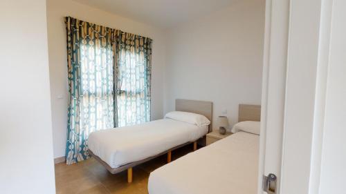 2 Betten in einem Zimmer mit Fenster in der Unterkunft Licuala by Oliva Nova in Oliva