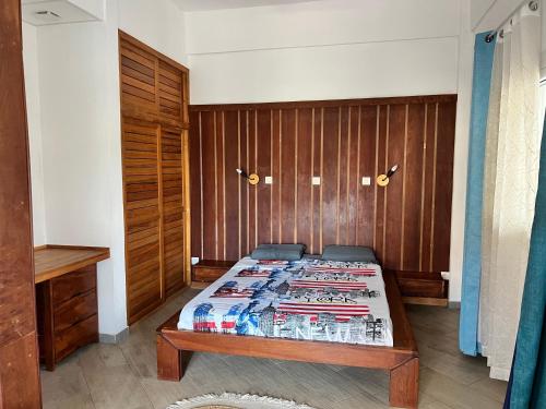 a bedroom with a bed and a wooden wall at Résidence Bleu Rivage in Diego Suarez