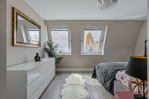 a bedroom with a bed with a white dresser and two windows at Green Diamond by Creatick Apartments in Brighton & Hove