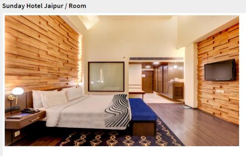 a hotel room with a bed and a flat screen tv at Sunday Hotel Jaipur in Jaipur