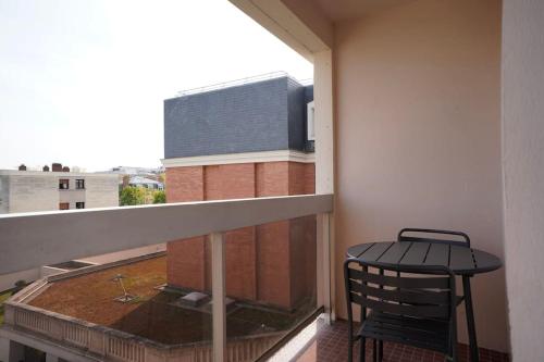 un balcon avec une chaise et une table sur un immeuble dans l'établissement Le Douillet - Aux portes de Paris - 323B, à Rueil-Malmaison
