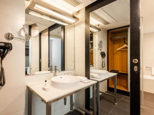 twee wastafels in een badkamer met twee spiegels bij Sunday Hotel Chandigarh Zirakpur in Zirakpur