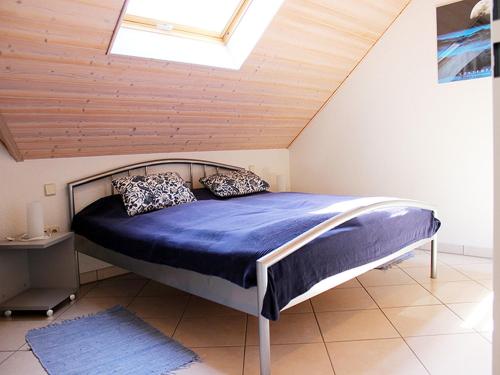 - une chambre avec un lit doté de draps bleus et une lucarne dans l'établissement Haus Birkenmeier, à Fribourg-en-Brisgau