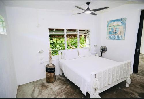 1 dormitorio blanco con 1 cama blanca y ventilador de techo en Banana Bay Beach Club en Eton